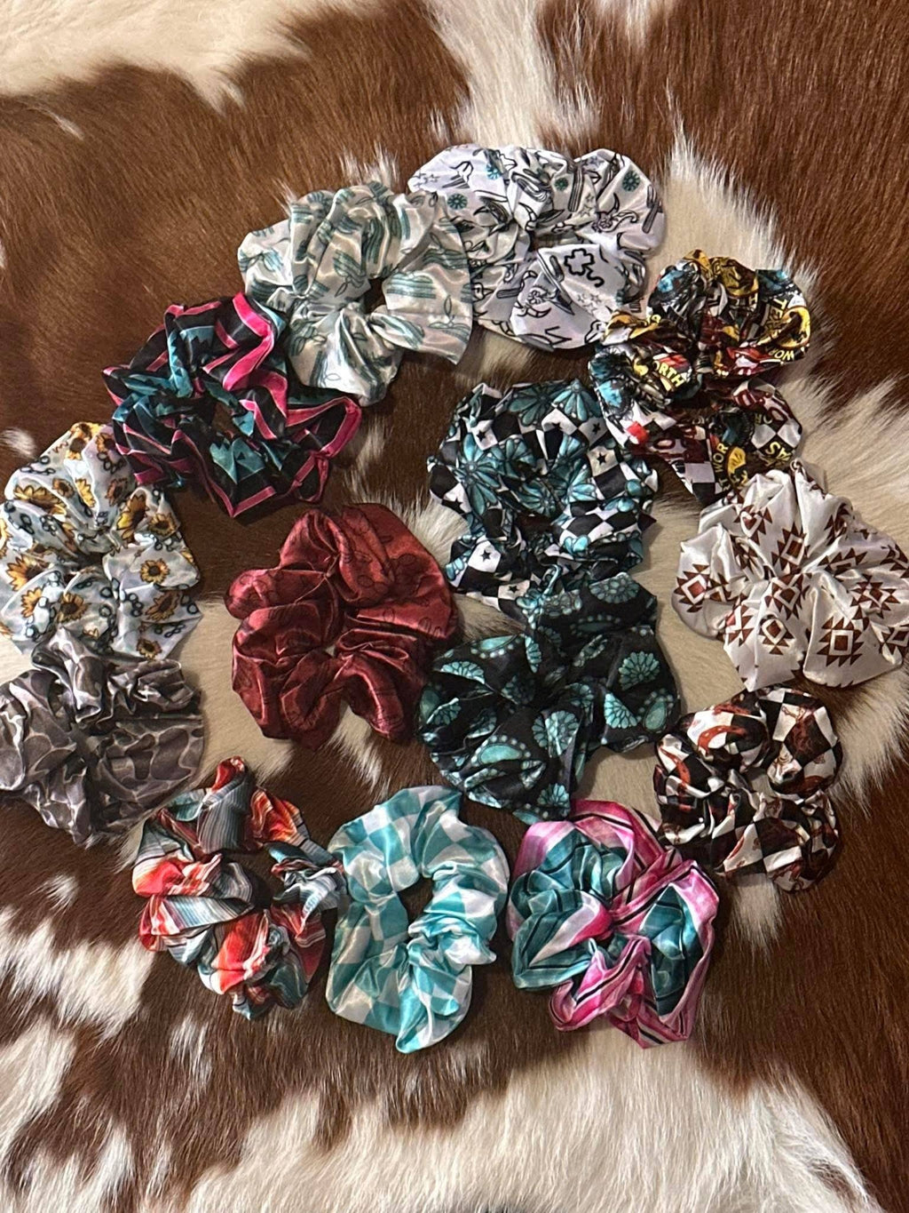 Assorted western themed scrunchies on a cow hide.